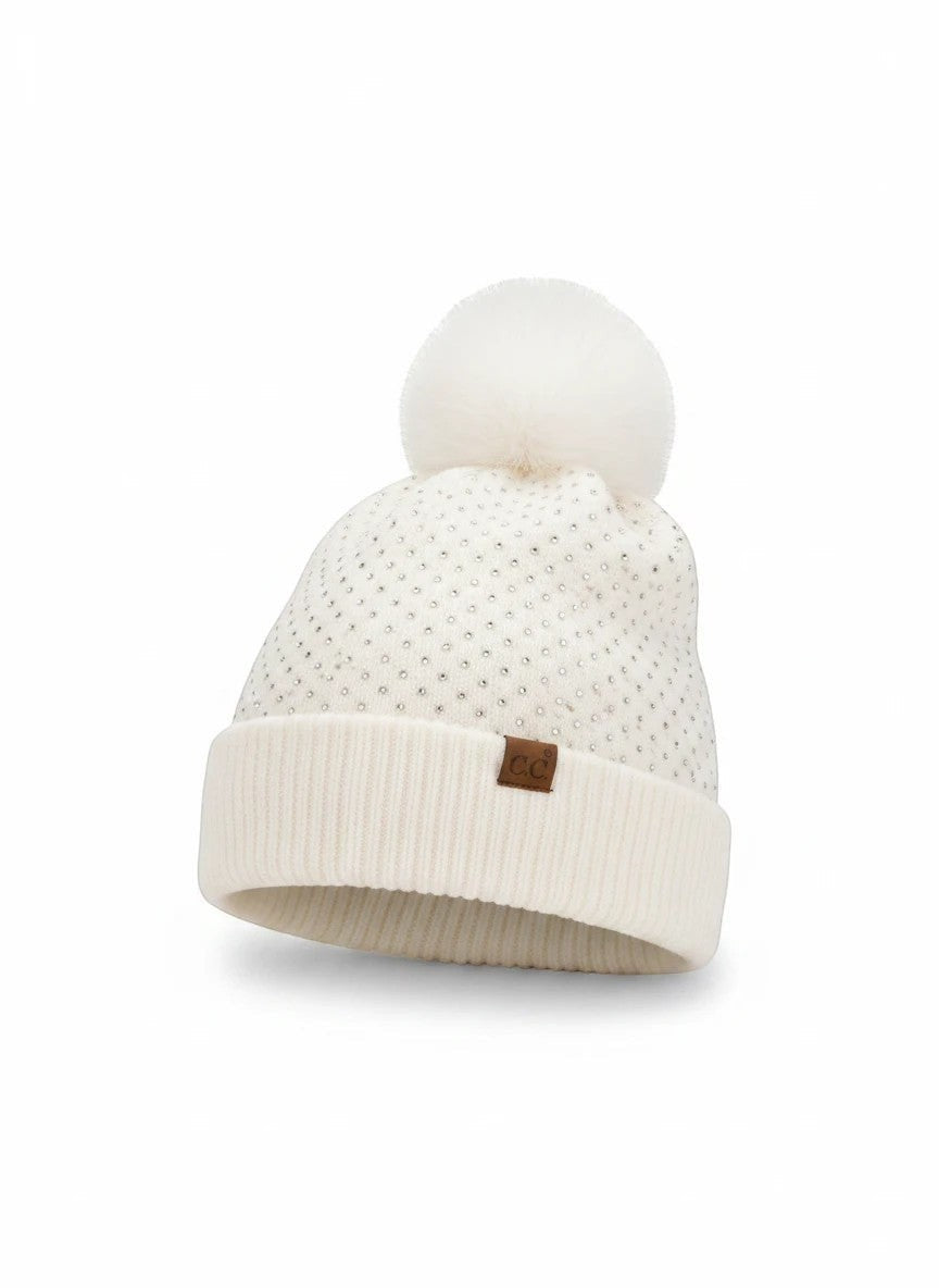Truly Contagious C.C® white knit beanie with allover rhinestone accents, fold-over cuff, and a fluffy faux fur pom pom.