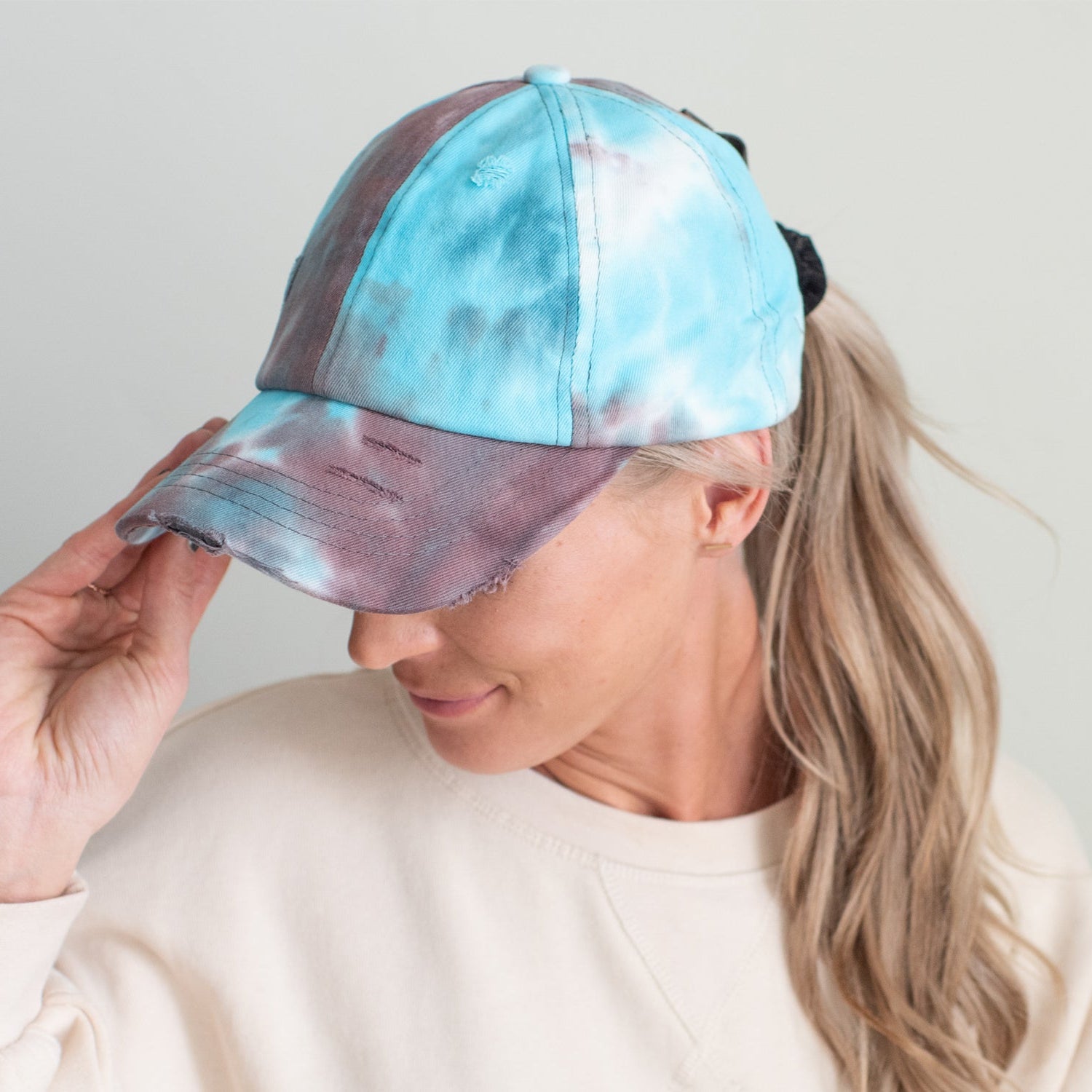Person wearing a tie-dye baseball cap with a light background