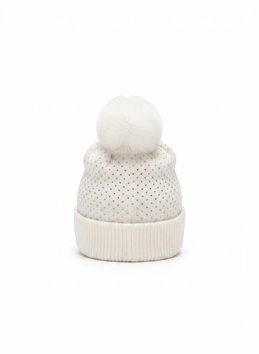 Truly Contagious white knit beanie with allover rhinestone accents and a large faux fur pom pom on a folded cuff.