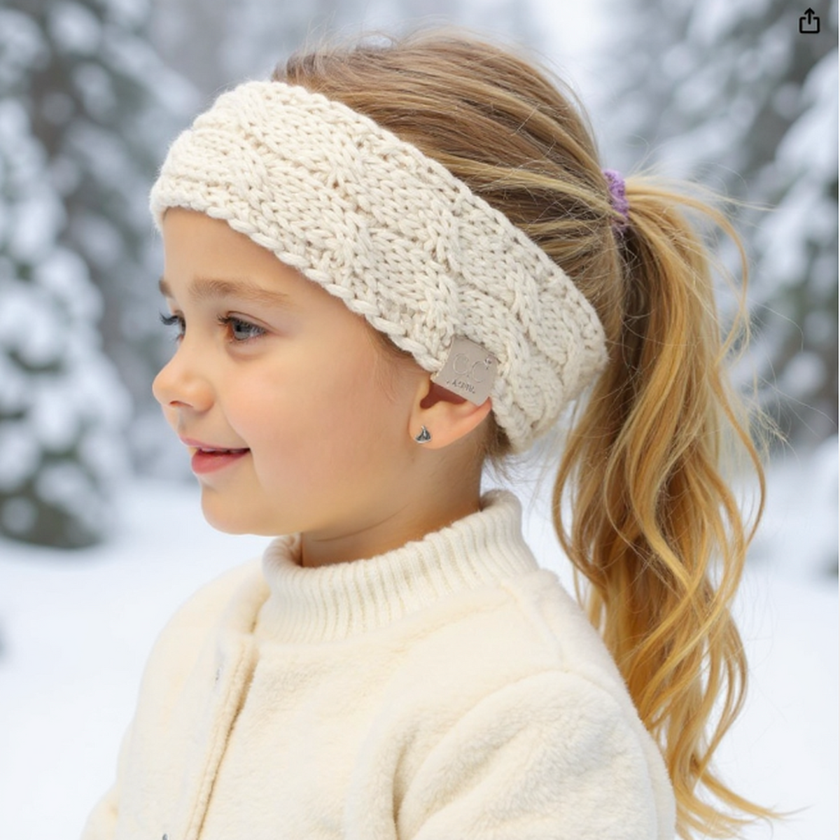 Child wearing a cream knitted headband in a snowy outdoor setting