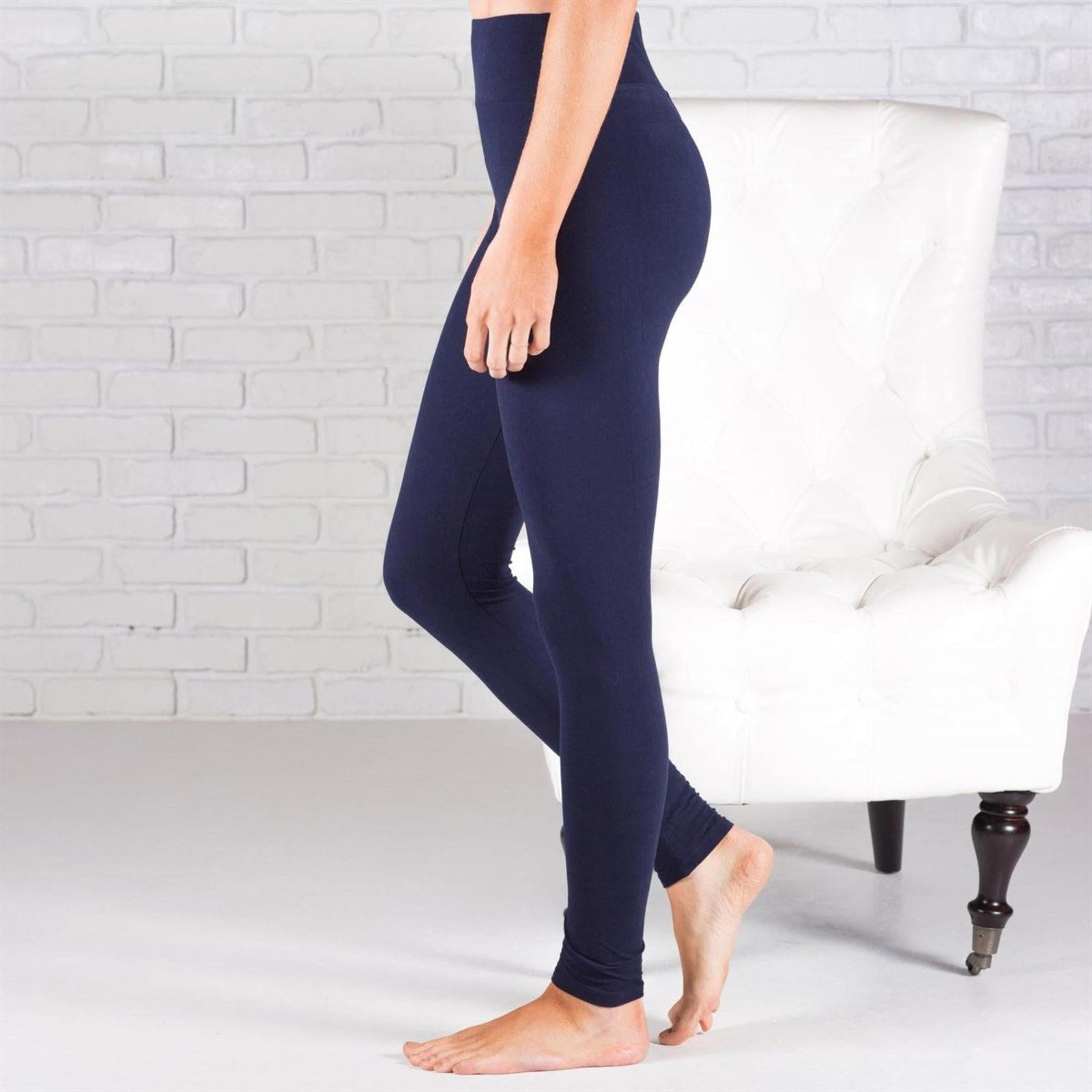 Person wearing navy leggings standing in front of a white brick wall.