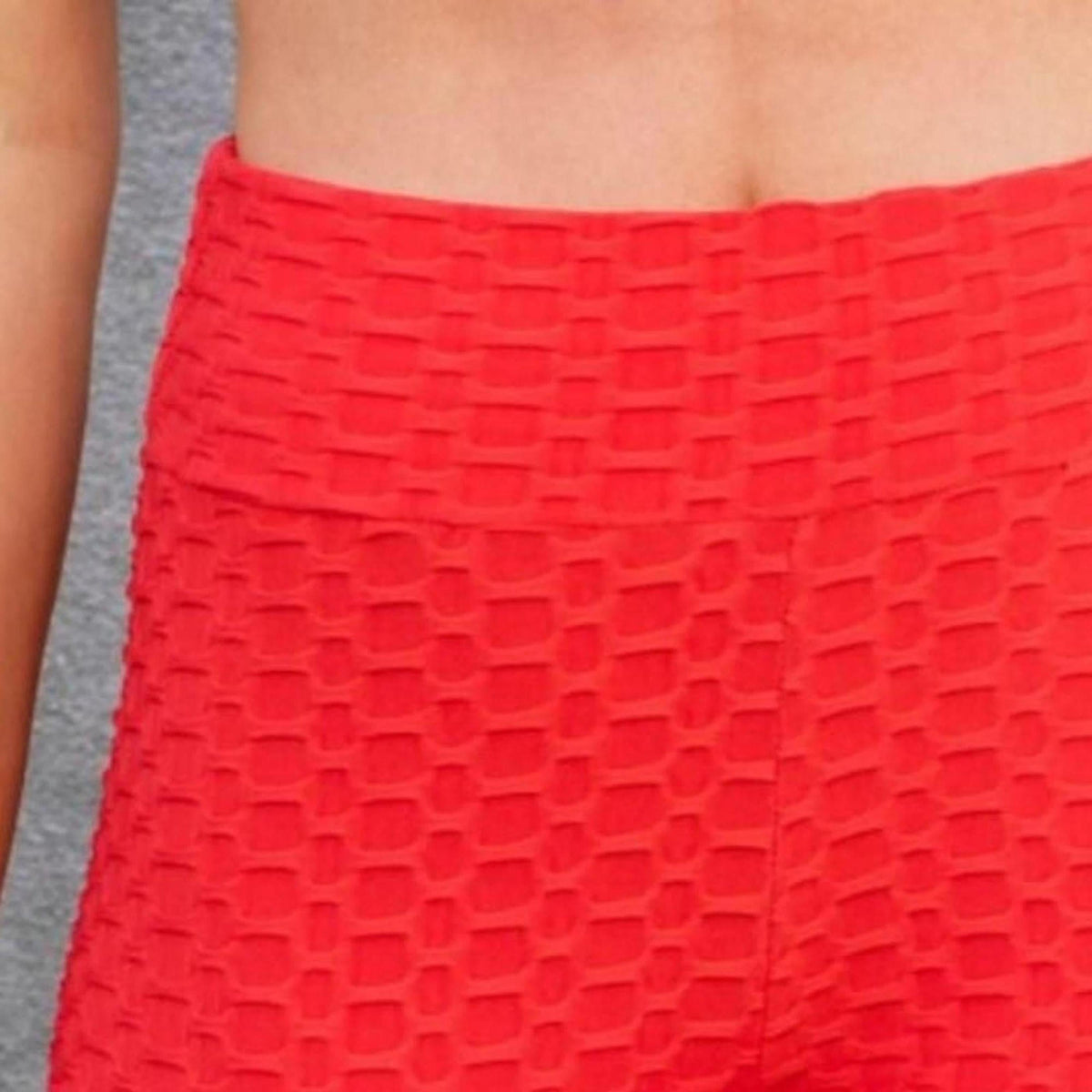 Person wearing red textured leggings against a gray background